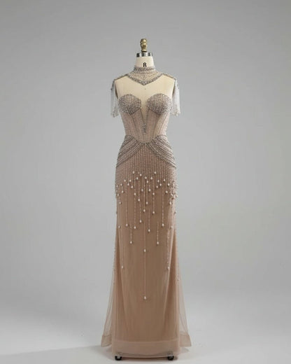 Beaded evening gown on a mannequin against a white paneled wall.